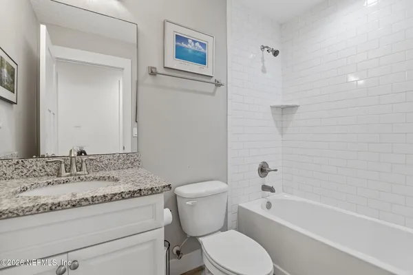 a bathroom with a granite countertop toilet a sink and a bathtub
