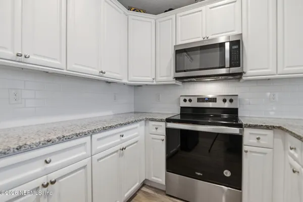 a kitchen with stainless steel appliances granite countertop white cabinets granite counter tops and a hard wood floors