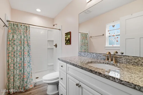 a bathroom with a granite countertop sink a toilet a shower and a mirror