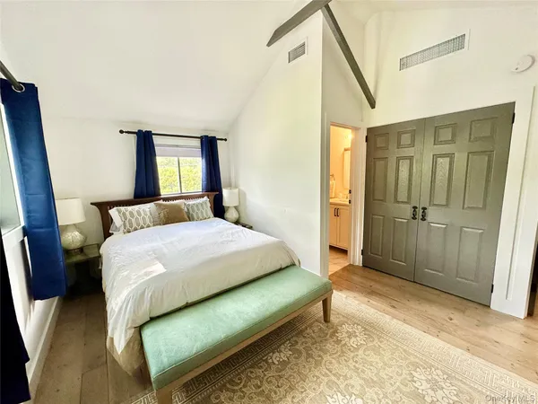a spacious bedroom with a bed and a mirror