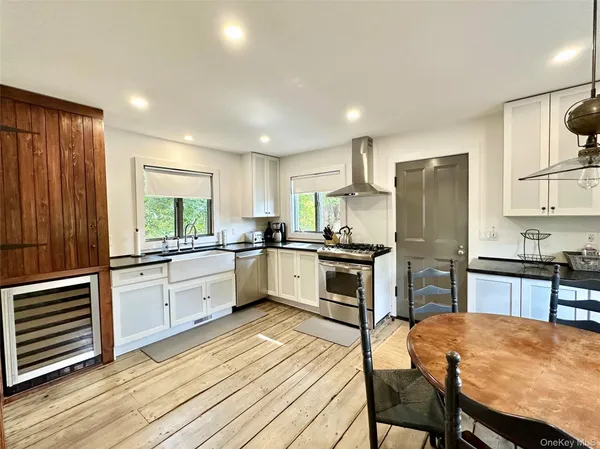 a kitchen with stainless steel appliances kitchen island granite countertop a refrigerator a stove a sink dishwasher with a dining table and chairs with wooden floor