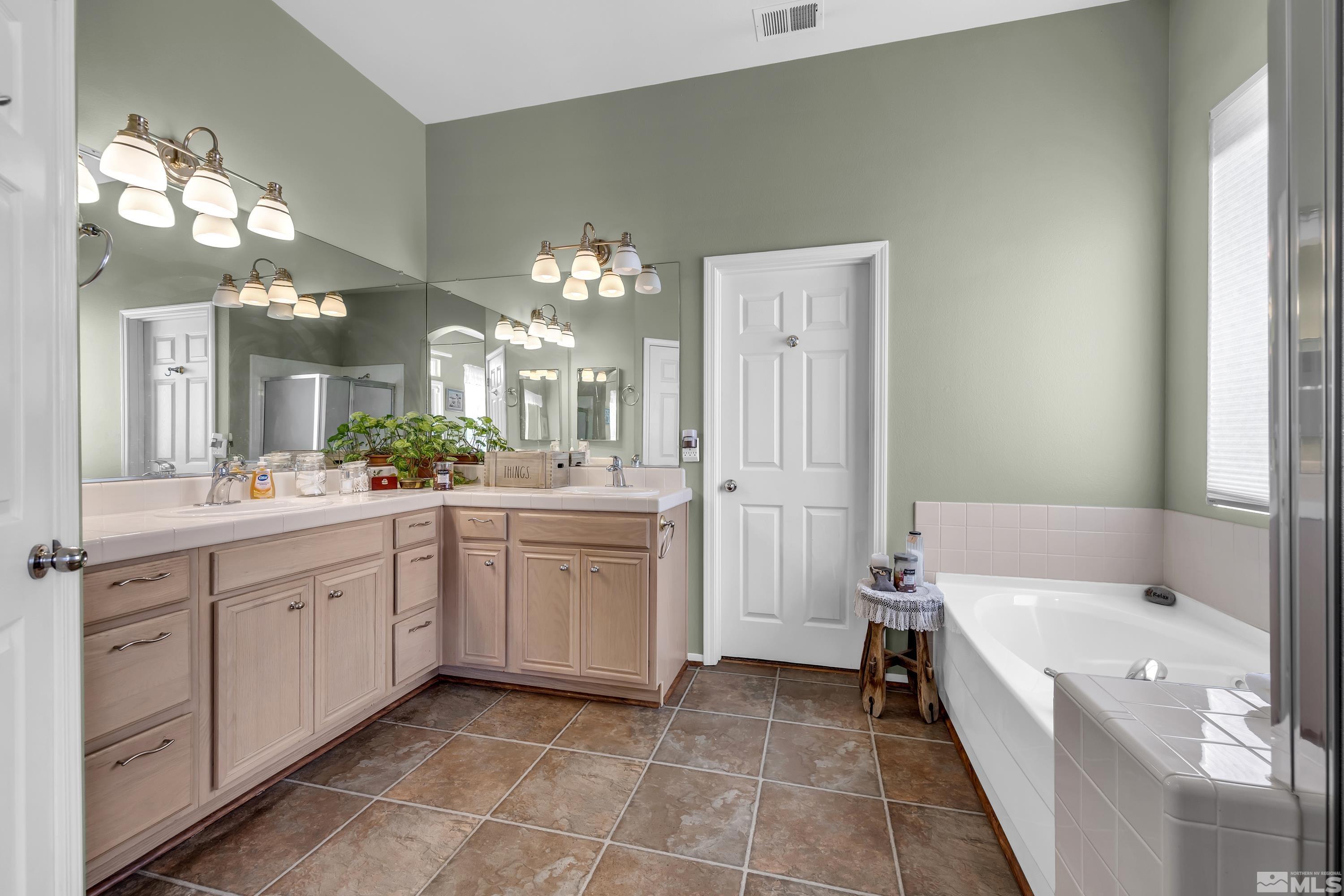 1496 Gaucho Lane Reno, NV 89521 - Photo 30 of 40 a spacious bathroom with a double vanity sink a mirror a bathtub and a shower