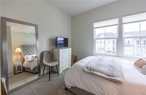 a bedroom with a bed chair and a large window