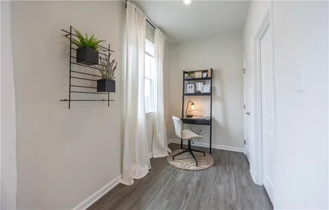 a view of a hallway with wooden floor and a potted plant