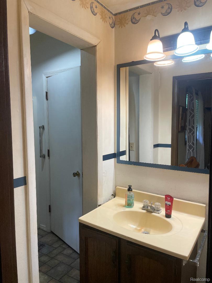 1866 South Barrie Road Bad Axe, MI 48413 - Photo 30 of 42 Integrated vanity with a composite countertop and sink, wood-finish cabinetry, and an overhead light fixture