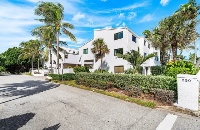 a front view of a house with a yard and palm trees