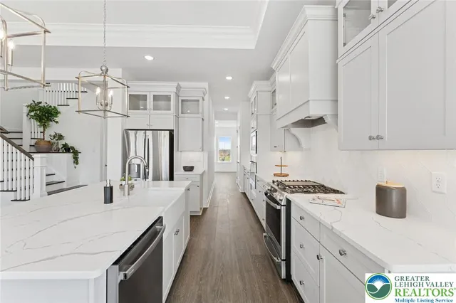 a kitchen with kitchen island a counter top space a stove a chimney wooden floor and cabinets