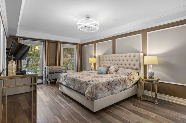 a bedroom with a large bed a chandelier and windows