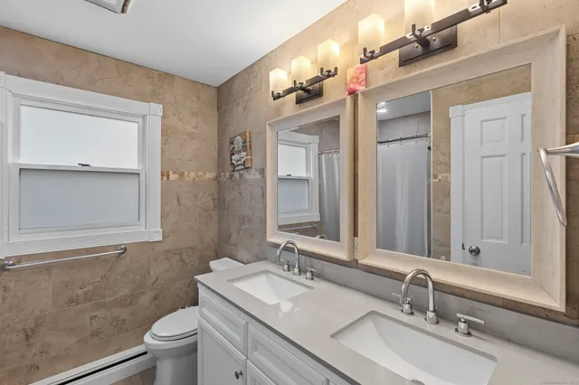 a bathroom with a double vanity sink toilet and mirror