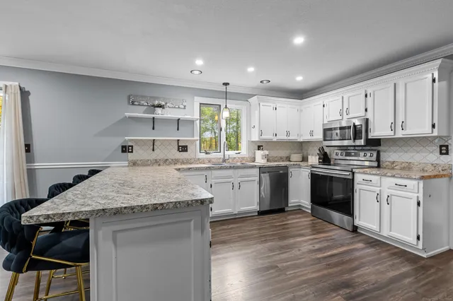 a kitchen with stainless steel appliances granite countertop wooden cabinets a sink dishwasher a stove and a refrigerator with wooden floor