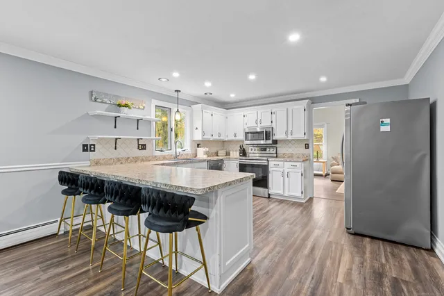 a kitchen with stainless steel appliances a table chairs refrigerator and cabinets