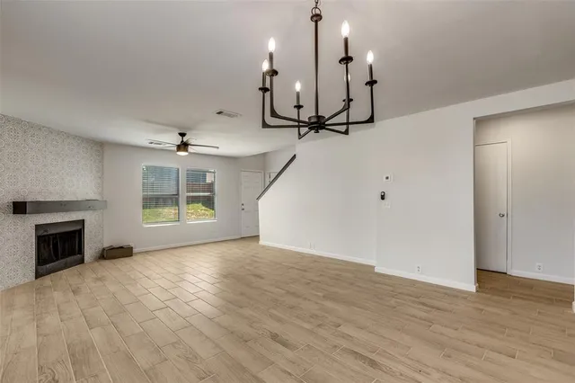 an empty room with wooden floor fireplace and windows
