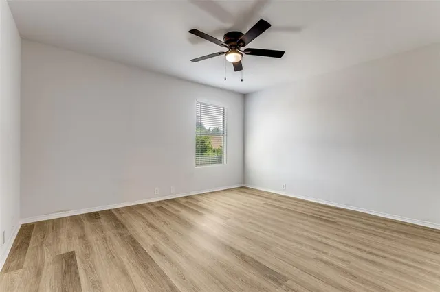 an empty room with a window and a ceiling fan