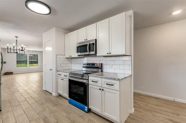 a kitchen with stainless steel appliances granite countertop a stove a sink and a microwave