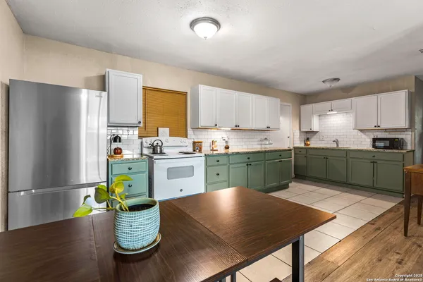 a kitchen with a refrigerator a sink dishwasher a stove with wooden cabinets and floor