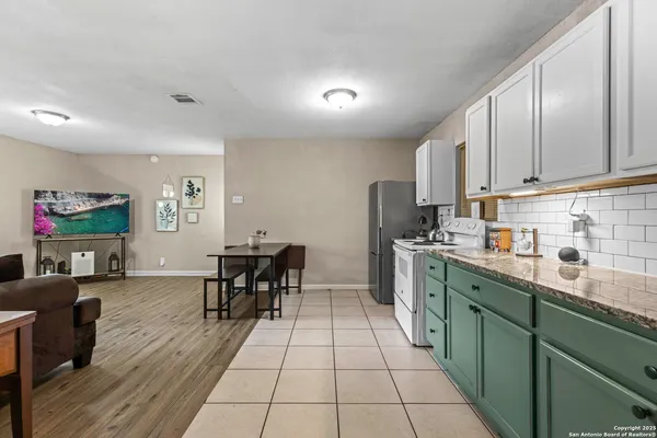 a kitchen with stainless steel appliances granite countertop a refrigerator a sink dishwasher a dining table and chairs with wooden floor