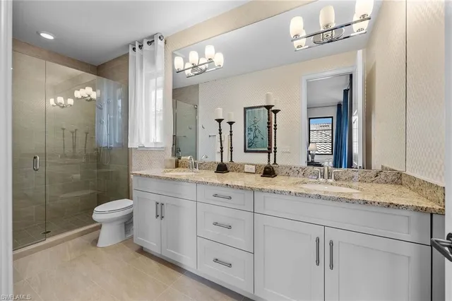 a bathroom with a granite countertop sink a toilet a mirror and shower