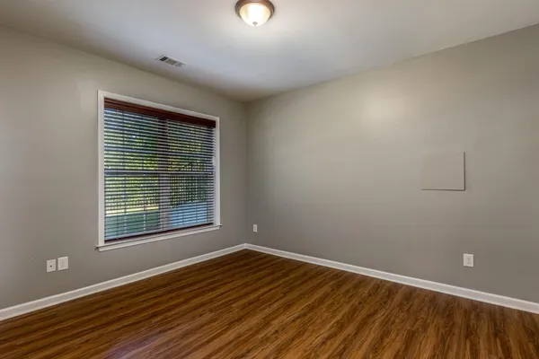 a view of an empty room with wooden floor and a window