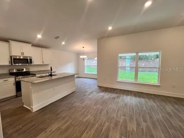 an open kitchen with kitchen island wooden floors and stainless steel appliances
