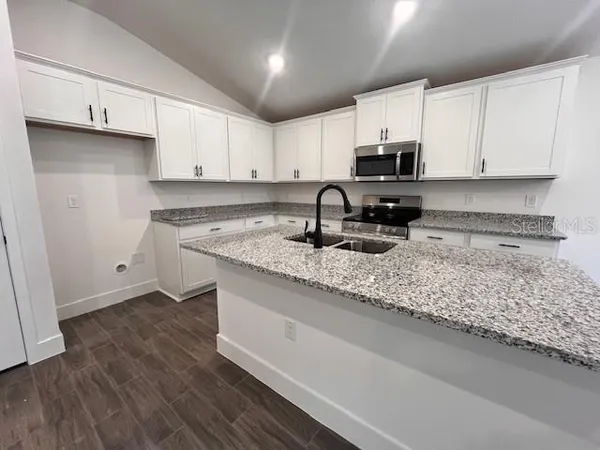 a kitchen with stainless steel appliances granite countertop a sink a stove a microwave and cabinets