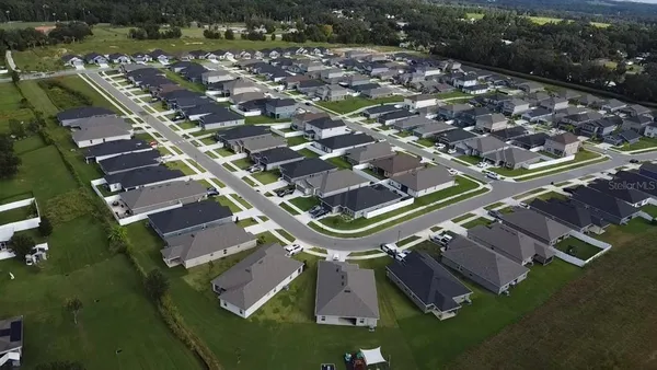 an aerial view of a residential houses with outdoor space and swimming pool