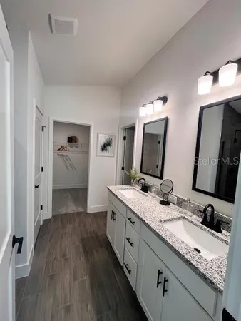a bathroom with a granite countertop double vanity sink and mirror