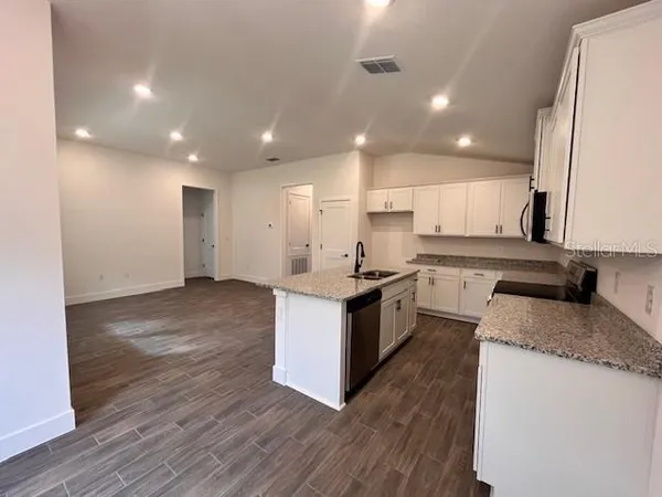 a large kitchen with granite countertop a large counter top a sink stainless steel appliances and cabinets