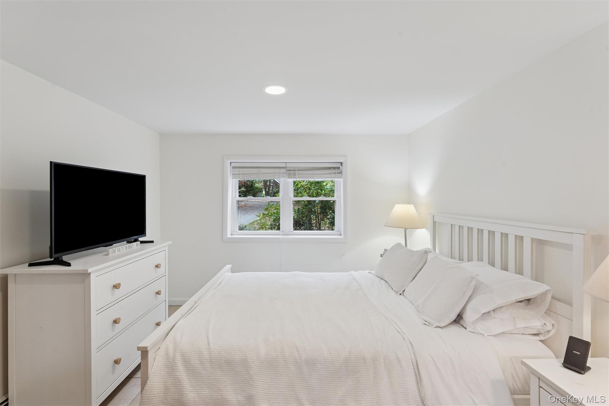 23 Old Main Road Quogue, NY 11959 - Photo 18 of 19 a bedroom with a bed and a flat screen tv