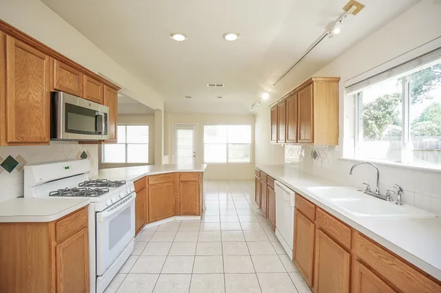a large kitchen with stainless steel appliances granite countertop a sink and cabinets