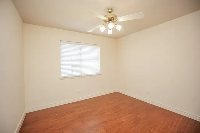 an empty room with a chandelier fan and windows