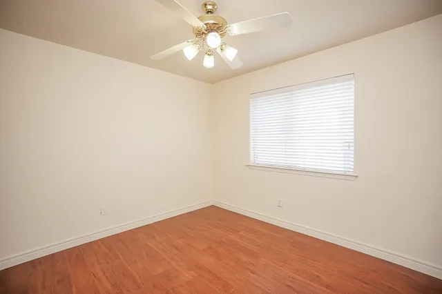 an empty room with a window and a ceiling fan