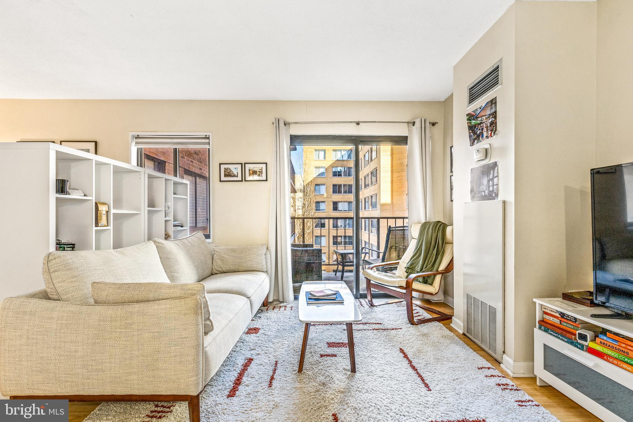 1718 P Street Northwest, Unit 509 Washington, DC 20036 - Photo 9 of 20 a living room with furniture a flat screen tv and a floor to ceiling window
