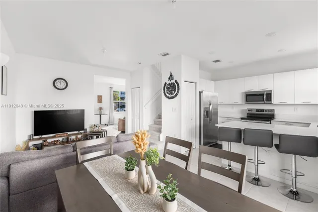 a kitchen with a dining table chairs appliances and cabinets
