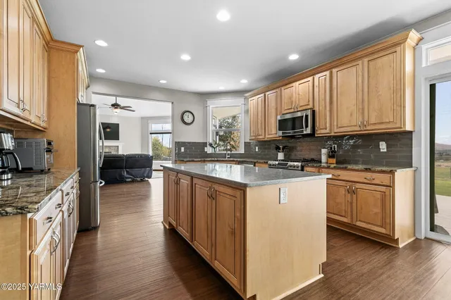 a large kitchen with stainless steel appliances granite countertop a stove sink and cabinets