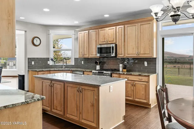 a kitchen with stainless steel appliances granite countertop a stove a sink dishwasher and a microwave oven with wooden cabinets