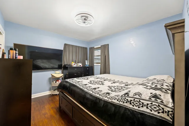 a bedroom with a bed and a dresser with wooden floor