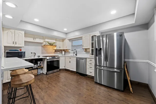 a kitchen with a refrigerator a sink dishwasher and a stove top oven with wooden floor