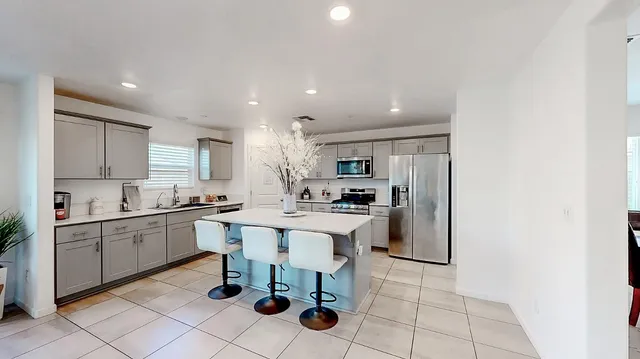 a kitchen with stainless steel appliances a table and chairs in it