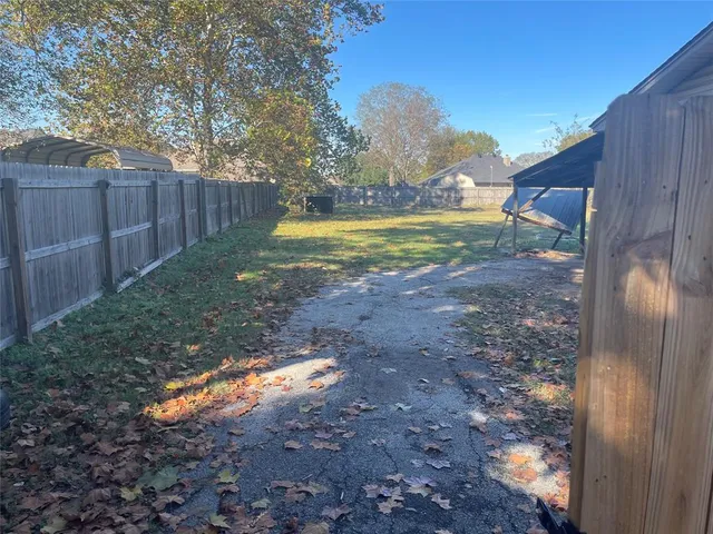 a view of a swimming pool with a yard and wooden fence