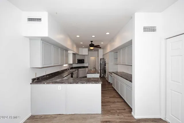 a large white kitchen with a sink and dishwasher a stove top oven with wooden floor
