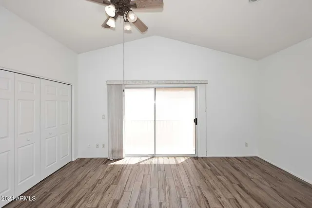 an empty room with wooden floor chandelier fan and windows