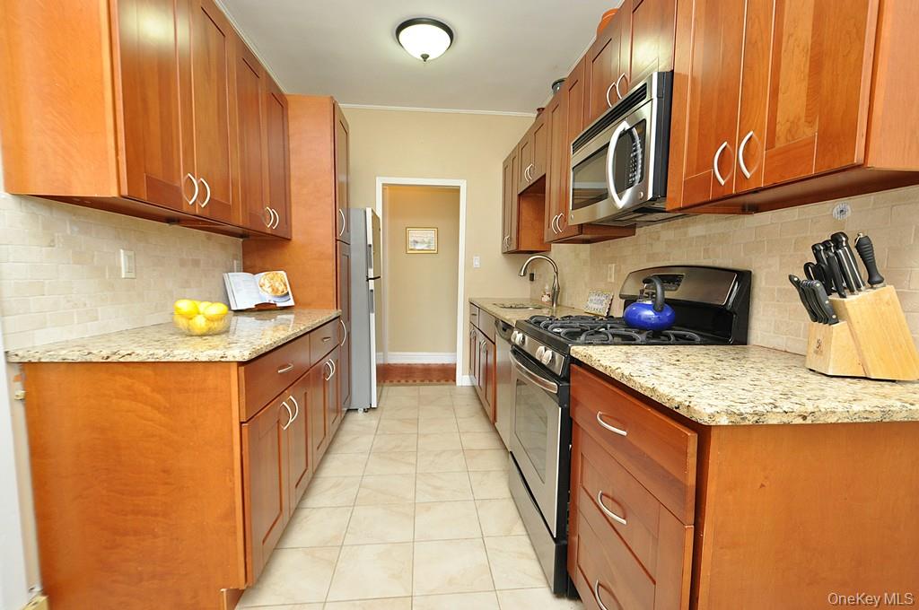 143 Garth Road, Unit 5J Scarsdale, NY 10583 - Photo 26 of 47 a kitchen with stainless steel appliances granite countertop a sink stove and cabinets