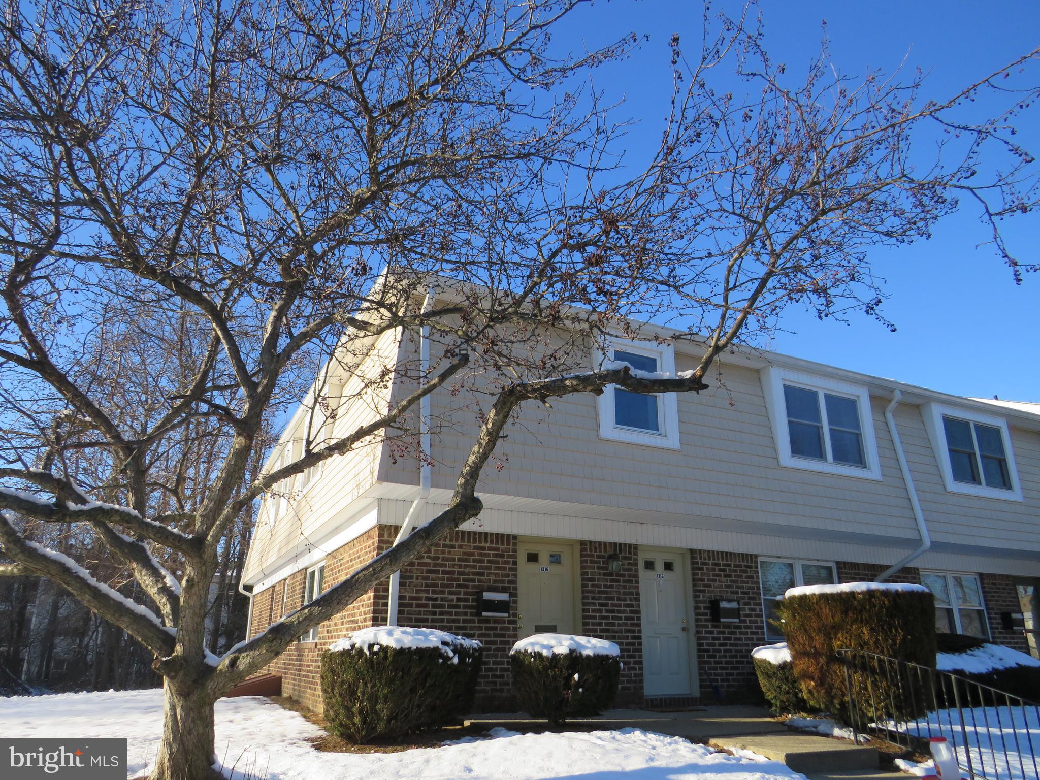 a view of a brick house with large windows and a large tree