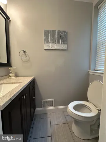 a bathroom with a granite countertop toilet and a sink