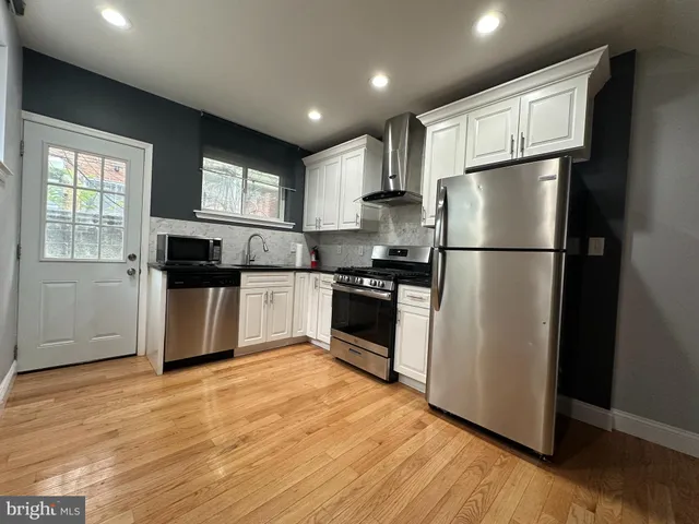a kitchen with kitchen island granite countertop a refrigerator and a stove top oven