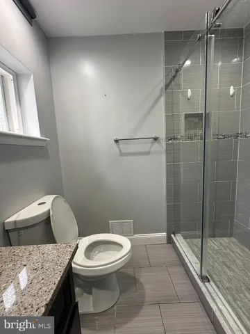 a bathroom with a granite countertop toilet and a shower