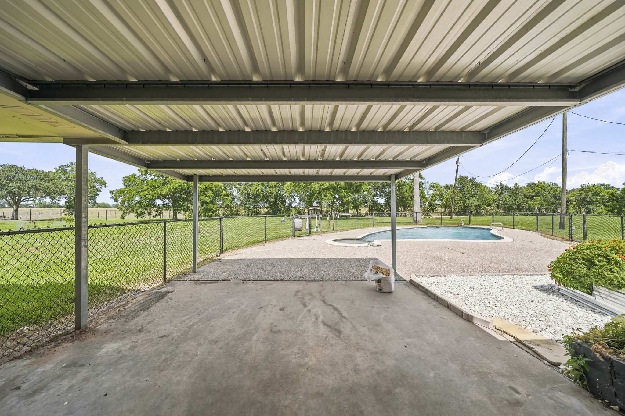 302 Country Road 893 Angleton, TX 77515 - Photo 24 of 26 Large covered patio area overlooking a fenced backyard with a swimming pool, surrounded by lush greenery, offering a perfect outdoor retreat.