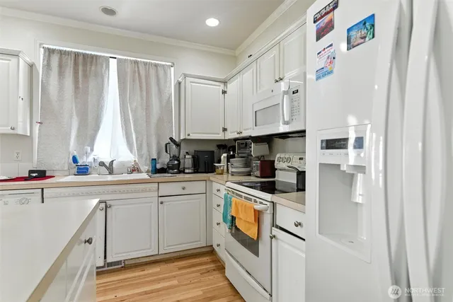 a kitchen with stainless steel appliances granite countertop white cabinets and white appliances