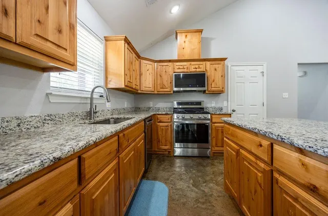 a kitchen with stainless steel appliances granite countertop a stove sink and a microwave