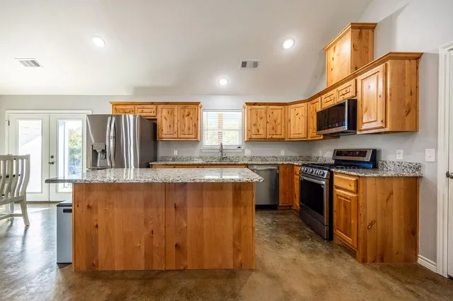 a kitchen with stainless steel appliances granite countertop a stove a sink and a microwave